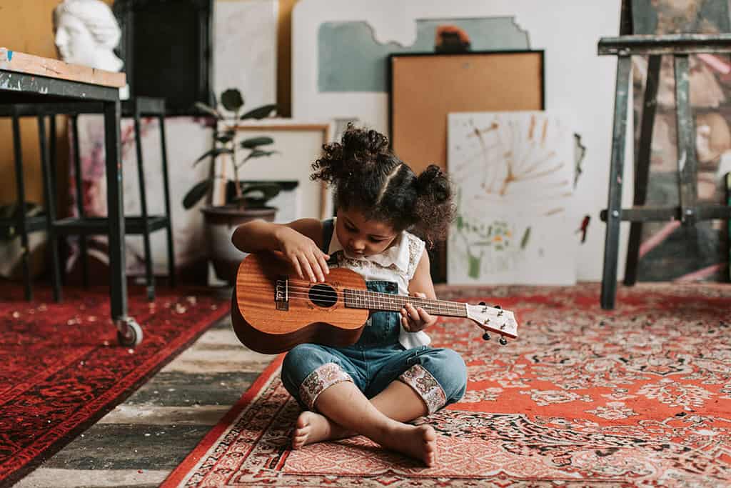 Young Girl Playing Guitar on Floor