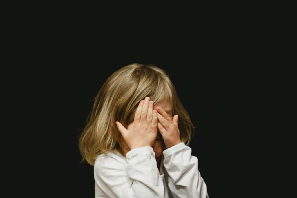 Child Hiding Behind Hands
