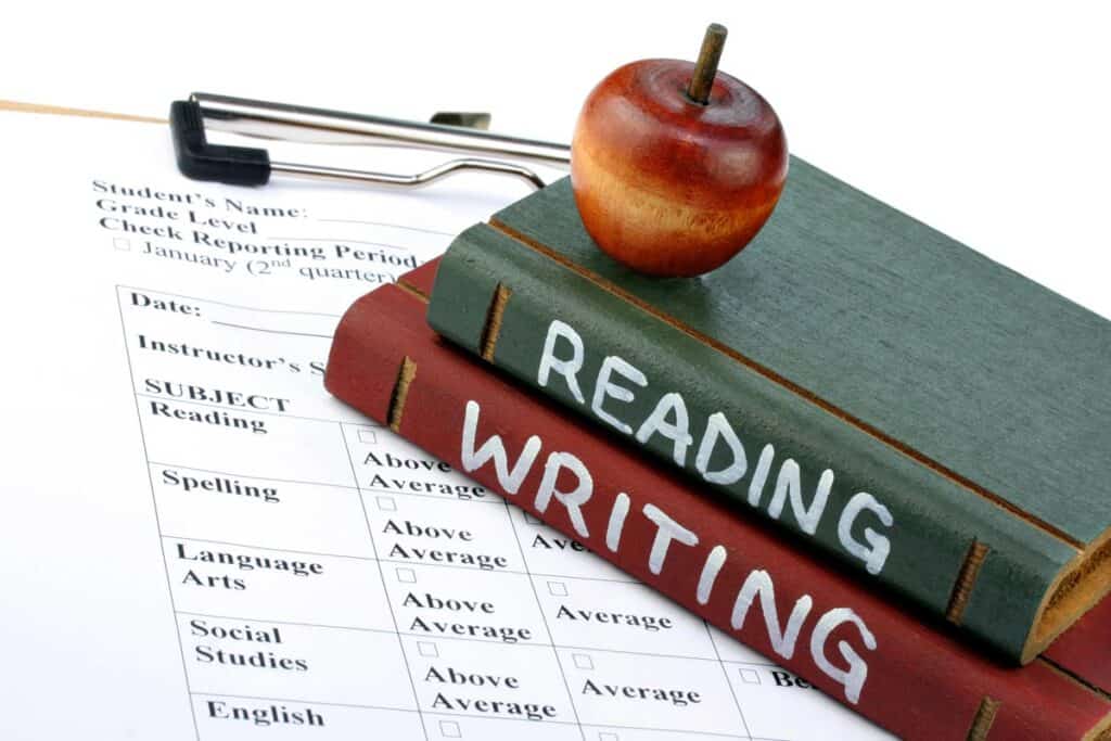 Wooden apple and books which say Reading and Writing on a report card