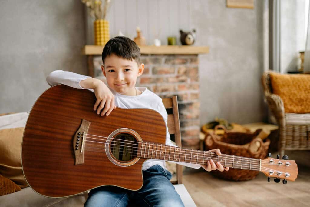 Boy smiling holding an acoustic guitar